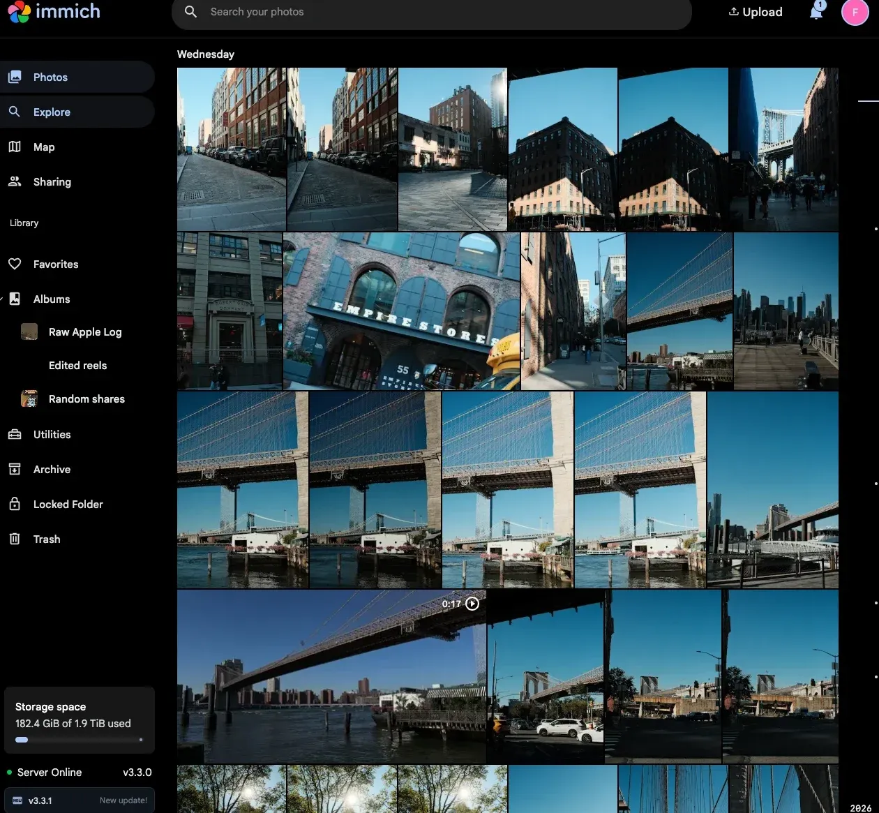 The Immich web timeline showing a day of New York footage: Dumbo streets, the Empire Stores building, the Manhattan and Brooklyn bridges, and a 17-second video, with albums including Raw Apple Log in the sidebar.